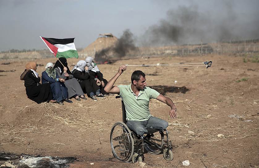 Сектор Газа. Палестинец кидает камни в израильских военных  