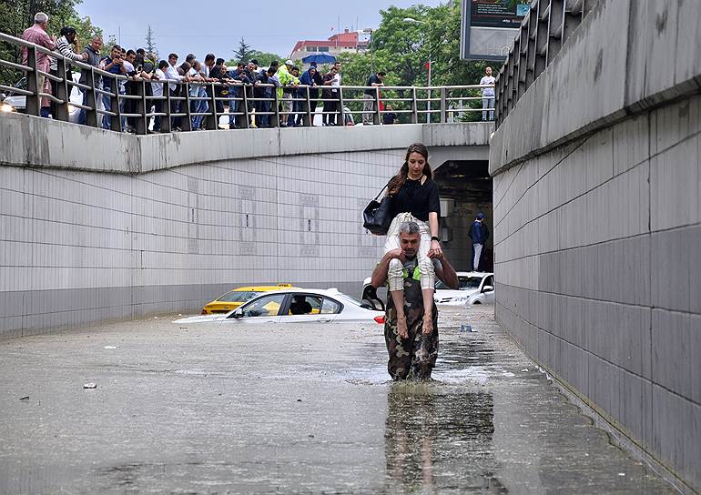 Анкара, Турция. Мужчина несет на плечах женщину по затопленной улице 