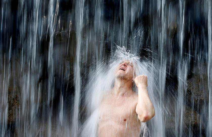 Минск, Белоруссия. Мужчина охлаждается в водопаде в жаркий день