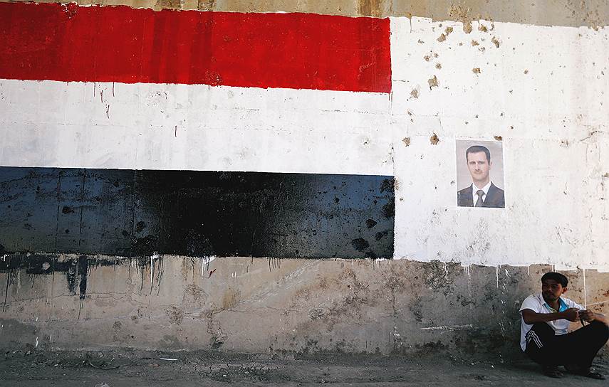 Талбиси, Сирия. Мужчина сидит рядом с портретом президента Сирии Башара Асада во время открытия восстановленной дороги между Хомсом и Хамой
