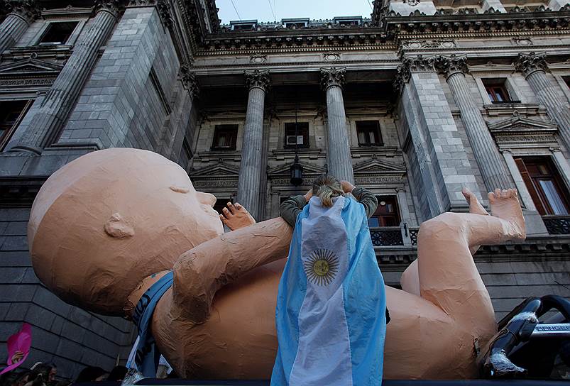 Буэнос-Айрес, Аргентина. Завернутая в национальный флаг участница демонстрации против абортов стоит у здания конгресса 
