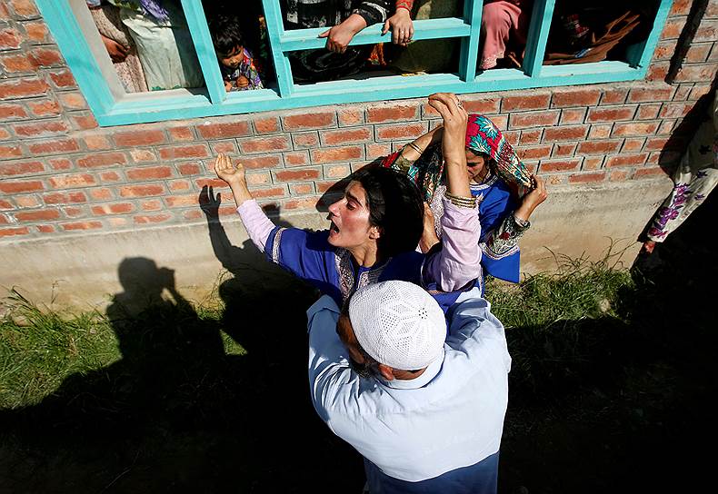 Округ Шопиан, Индия. Мужчина пытается успокоить женщину на похоронах местного жителя, погибшего в столкновениях с индийскими силовиками 