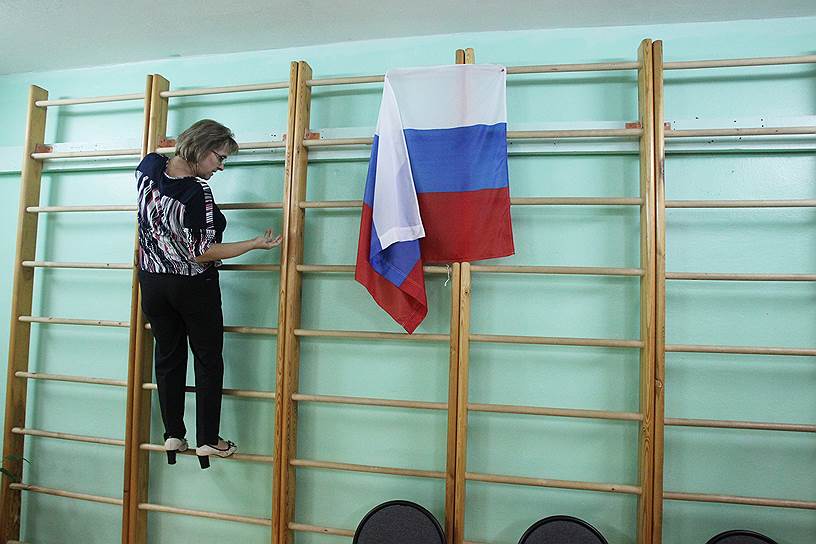 Нижний Новгород. Работница избирательной комиссии снимает российский триколор со шведской стенки