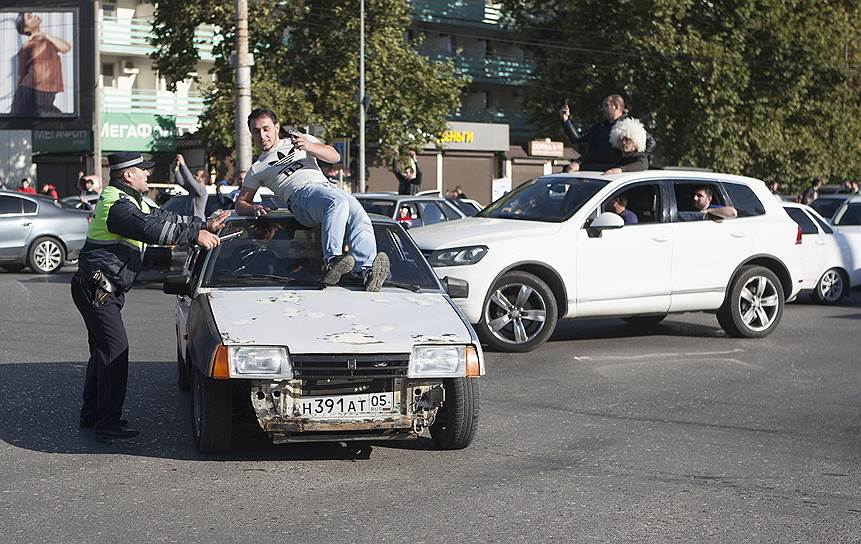 Сотрудник ДПС пытается остановить машину на празднованиях победы Хабиба Нурмагомедова в Махачкале