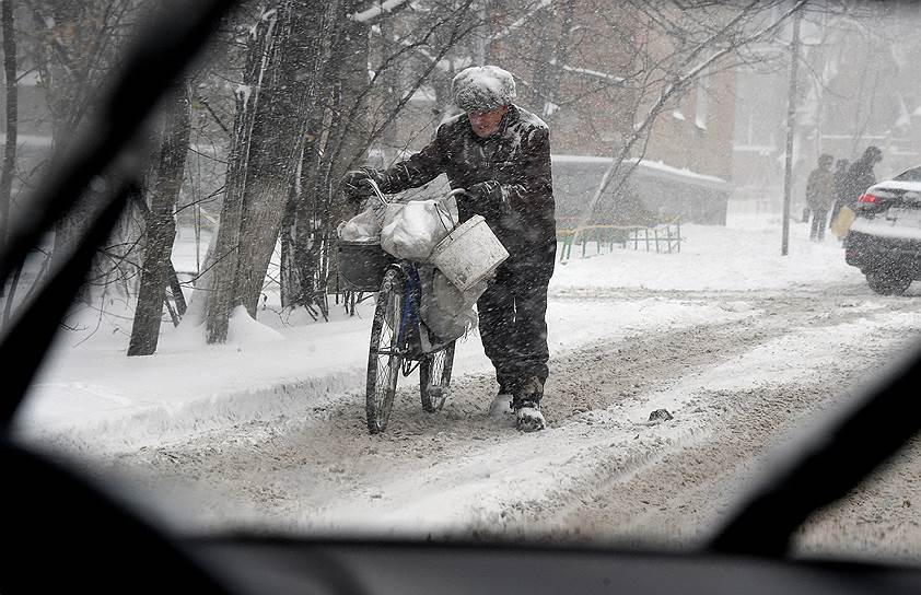 Ростовская область. Пожилой мужчина с велосипедом на обочине дороги во время снегопада