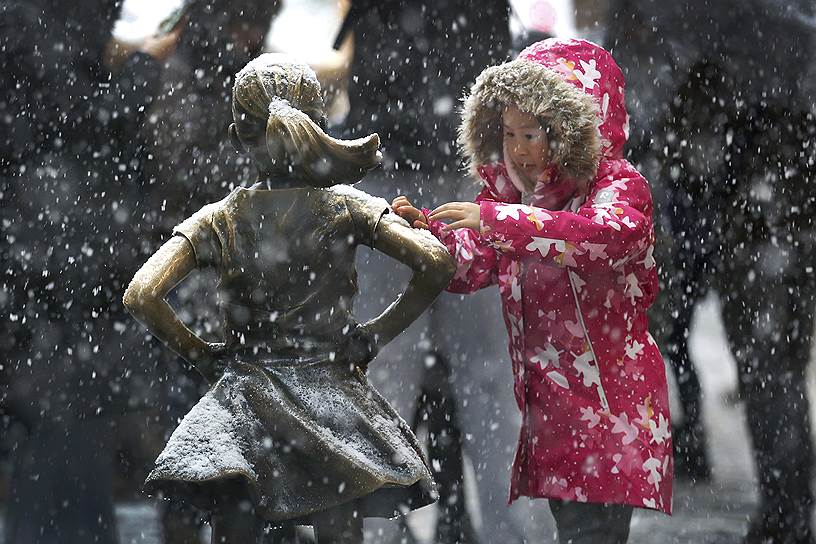Нью-Йорк, США. Девочка смахивает снег со скульптуры «Бесстрашная девочка»