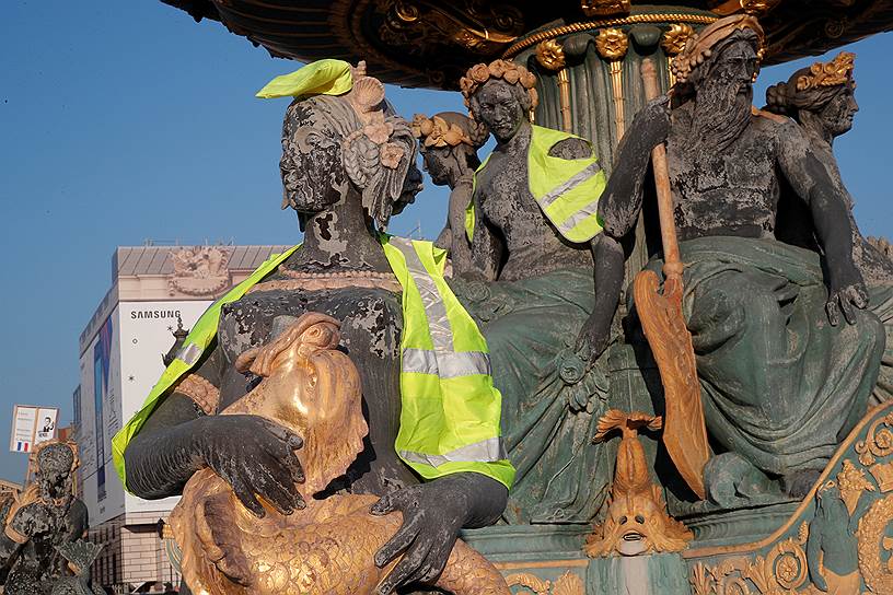 Желтые жилеты на статуях на площади Согласия в Париже