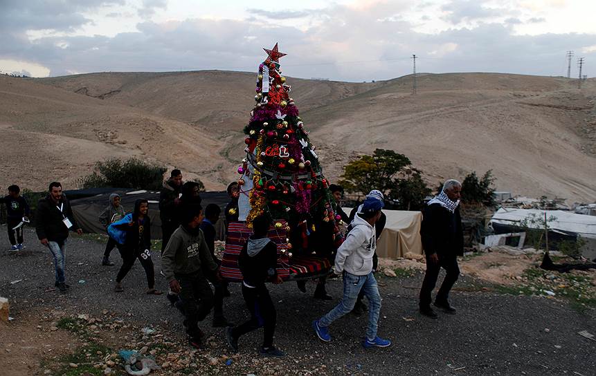 Деревня Хан аль-Ахмар, Западный берег реки Иордан. Палестинцы несут украшенную елку 