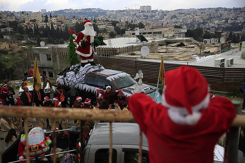 Назарет, Израиль. Арабский мальчик-христианин в костюме Санта-Клауса наблюдает за ежегодным рождественским парадом
