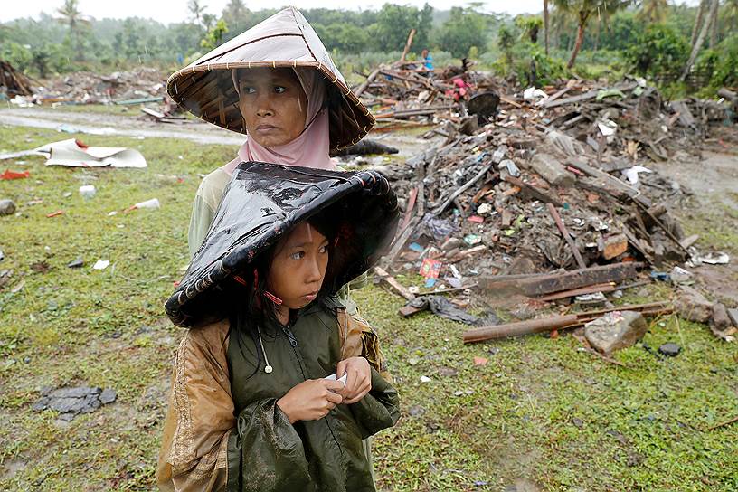 Сумур, Индонезия. Женщина с ребенком стоят около разрушенных после цунами построек