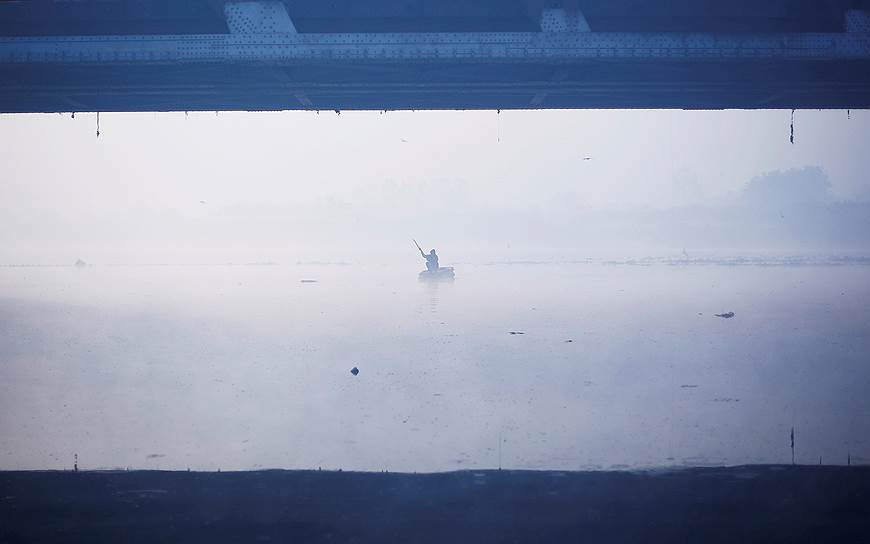 Нью-Дели, Индия. Мужчина на плоту плывет по реке Джамна
