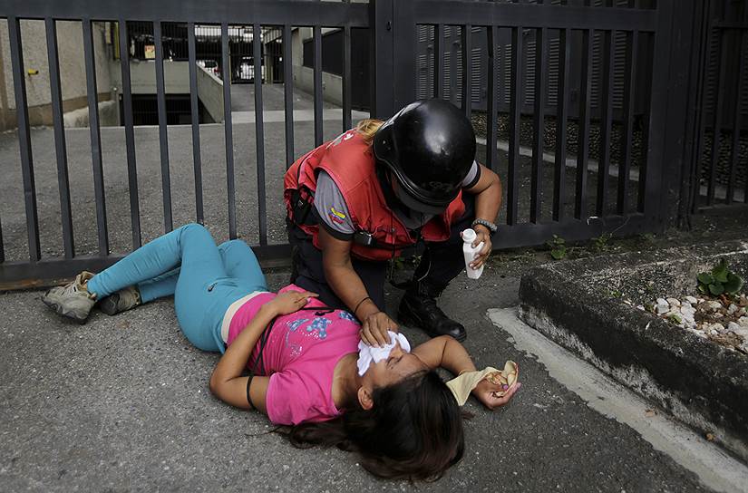 Женщине, пострадавшей от распыления слезоточивого газа в Каракасе, оказывают помощь