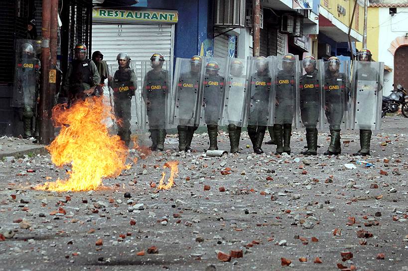 Полицейские во время столкновений с оппозиционерами в Каракасе
