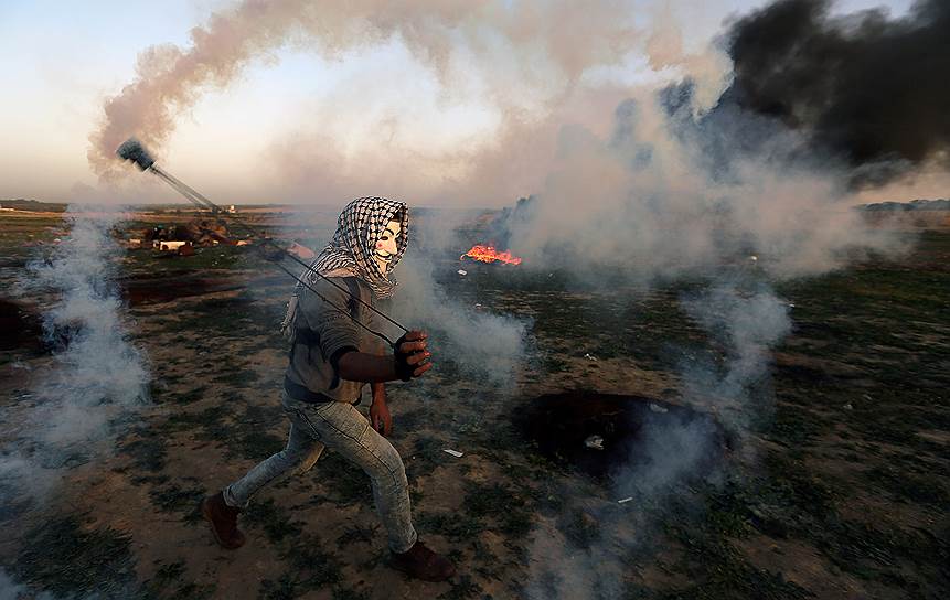 Сектор Газа. Палестинский демонстрант бросает емкость со слезоточивым газом 