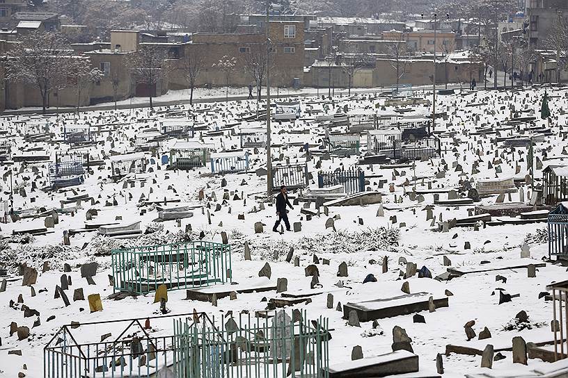 Кабул, Афганистан. Мужчина идет по заснеженному кладбищу