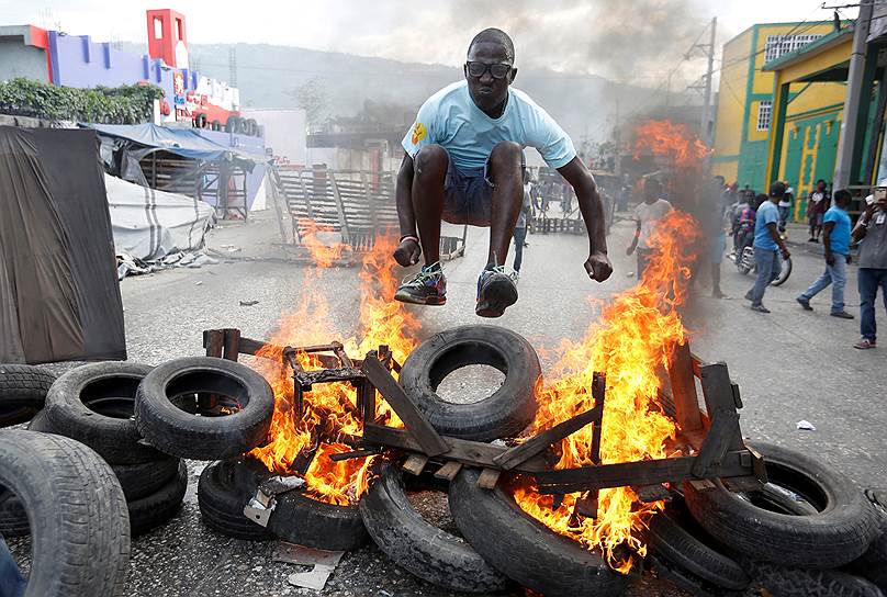 Порт-о-Пренс, Гаити. Протестующий прыгает через баррикады во время антиправительственной акции