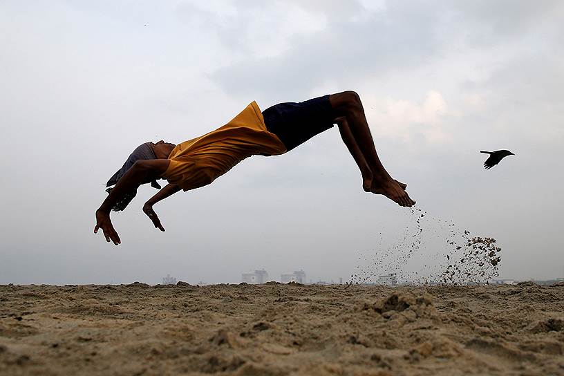 Керала, Индия. Мальчик тренируется прыгать на пляже