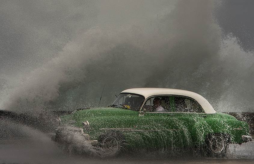 Гавана, Куба. Автомобиль в брызгах волны на набережной Малекон