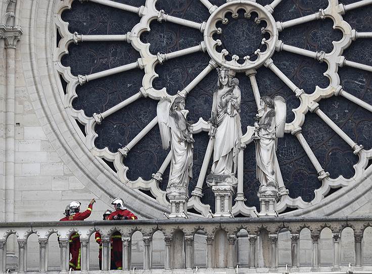 Париж, Франция. Пожарные разговаривают у главного окна-розетки собора Парижской богоматери 