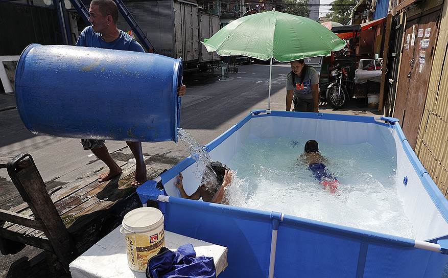 Манила, Филиппины. Дети спасаются от жары в уличном бассейне  