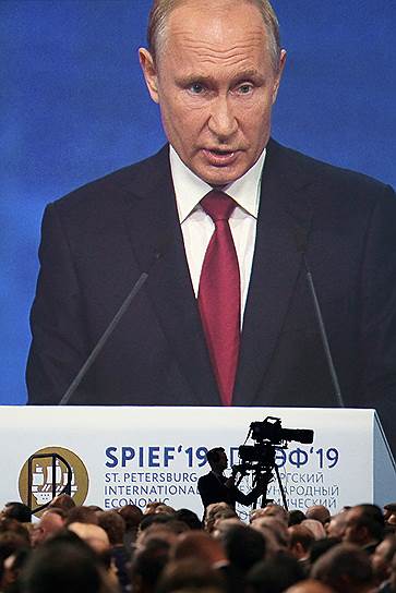 Президент России Владимир Путин (на экране) во время выступления на пленарном заседании