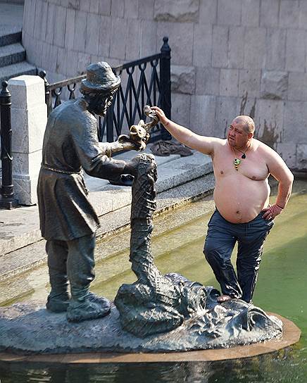 Москва, Россия. Мужчина в жаркую погоду у фонтана «Золотая рыбка» на Манежной площади