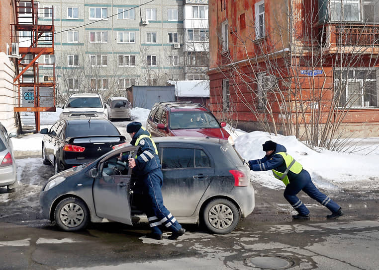 Сотрудники ДПС толкают автомобиль при выезде из двора жилого дома