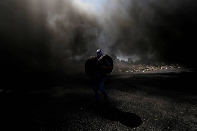 Бейт-Эль, Западный берег реки Иордан. Палестинец несет шины, чтобы сжечь их на акции протеста
