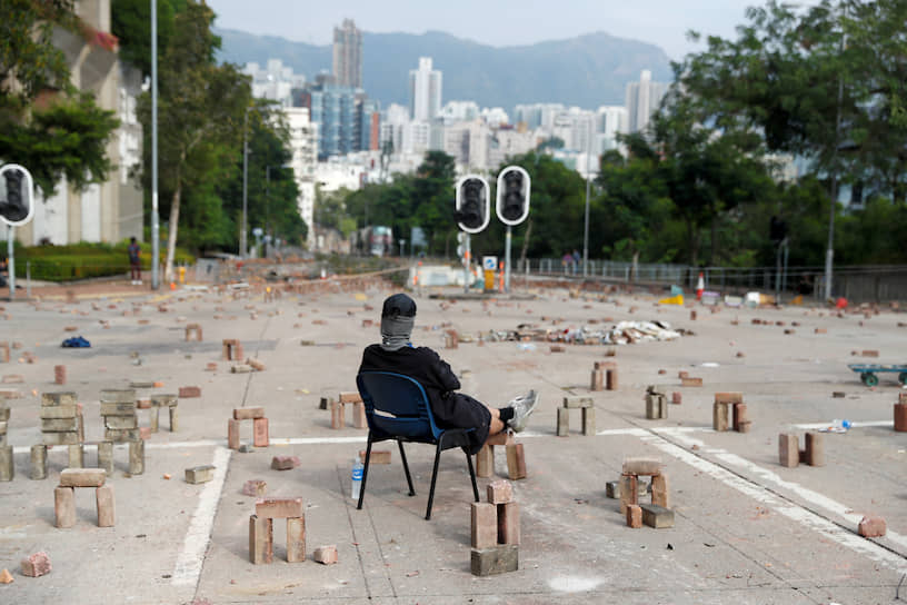 Гонконг, КНР. Протестующий сидит на перекрытой дороге рядом с университетом