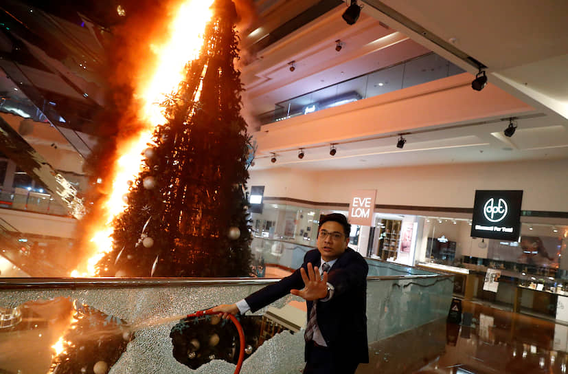 Гонконг, КНР. Мужчина пытается потушить загоревшуюся рождественскую ель в торговом центре