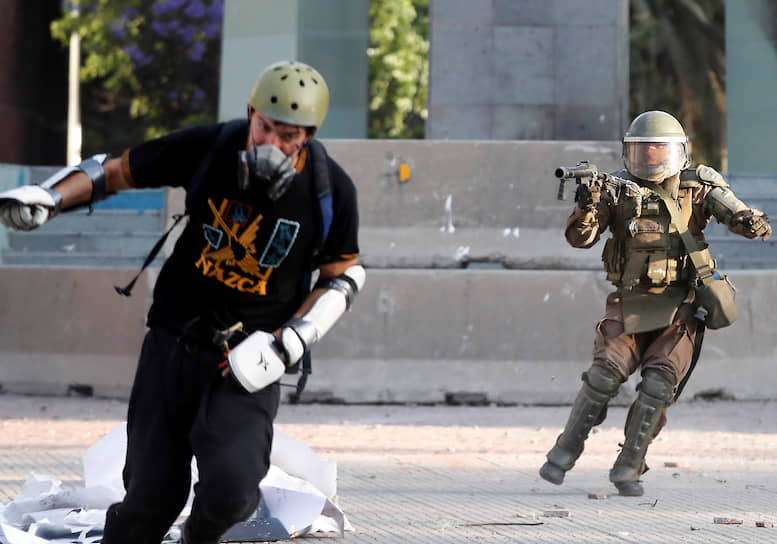 Сантьяго, Чили. Полицейский применяет слезоточивый газ против участника акции протеста