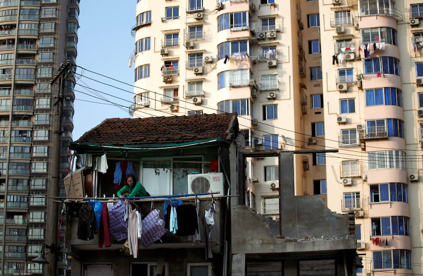 Шанхай, Китай. Женщина стоит на балконе дома, на месте которого должны построить многоэтажку