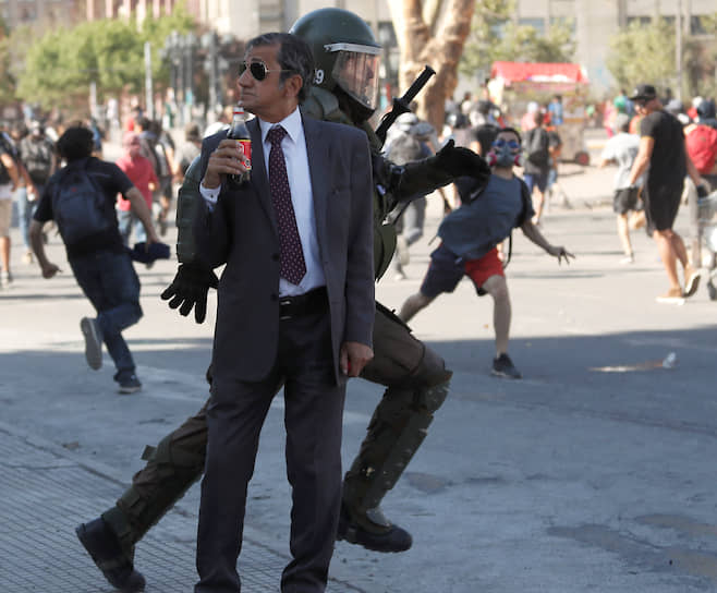Сантьяго, Чили. Мужчина пьет кока-колу во время разгона полицией антиправительственной демонстрации