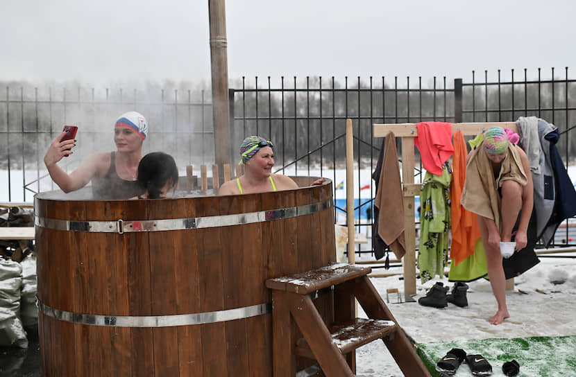 Тюмень, Россия. Участницы соревнований на Открытый кубок по зимнему плаванию греются в бочке с горячей водой