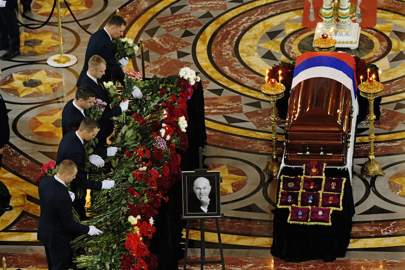 Закрытый гроб с покойным стоял по центру главного зала. Гроб был покрыт флагом России, за ним расставлены венки и цветы