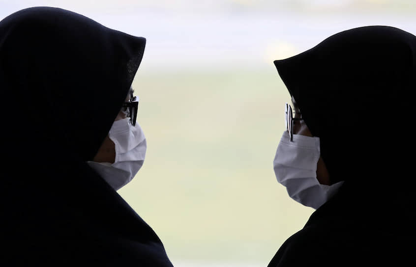 Сепанг, Малайзия. Две женщины в масках разговаривают друг с другом в аэропорту