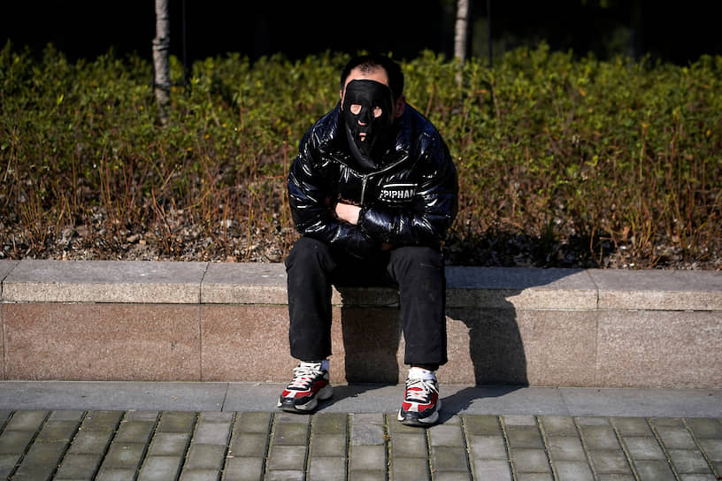 Мужчина в маске возле парка в Шанхае, где заболели более 300 человек