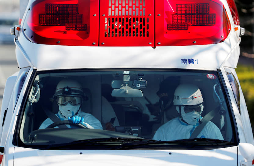 Работники скорой помощи в защитных костюмах предположительно везут в больницу человека с карантинного лайнера Diamond Princess (юг Токио, Япония)