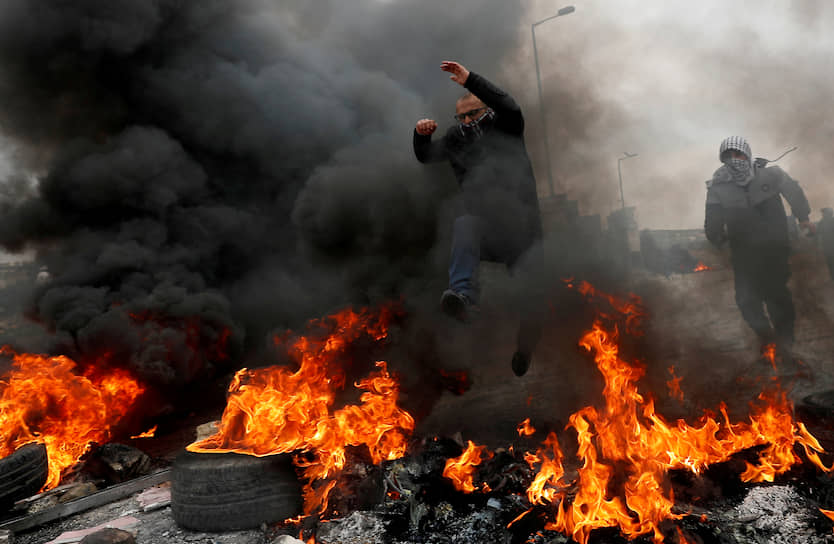 Бейт-Эль, Западный берег реки Иордан. Палестинец перепрыгивает через горящие шины во время акции протеста
