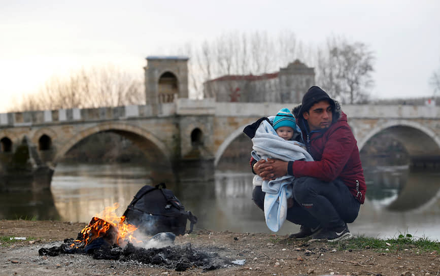 Эдирне, Турция. Мигрант с ребенком на руках у реки на границе с Грецией