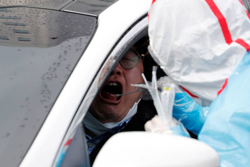 Тэгу, Южная Корея. Медик в защитном снаряжении тестирует водителя на наличие нового коронавируса