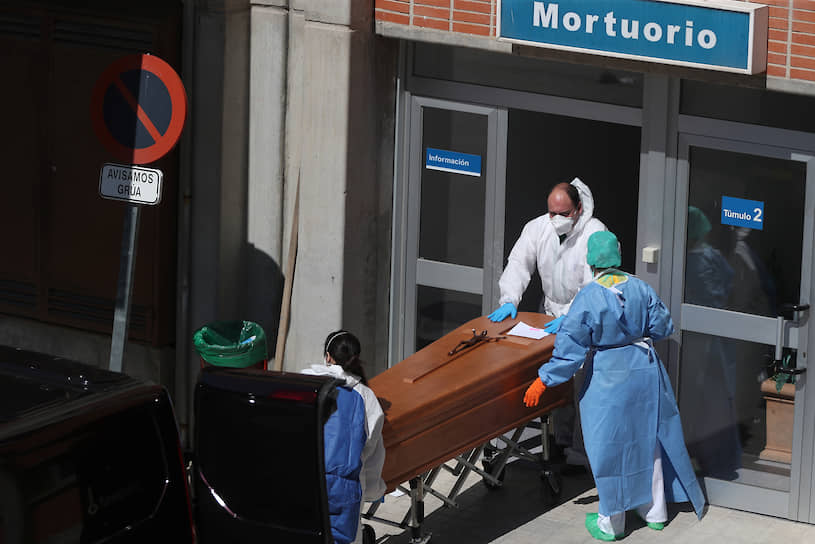 Испания. Похоронные работники в защитных костюмах выносят гроб из морга больницы в Леганесе