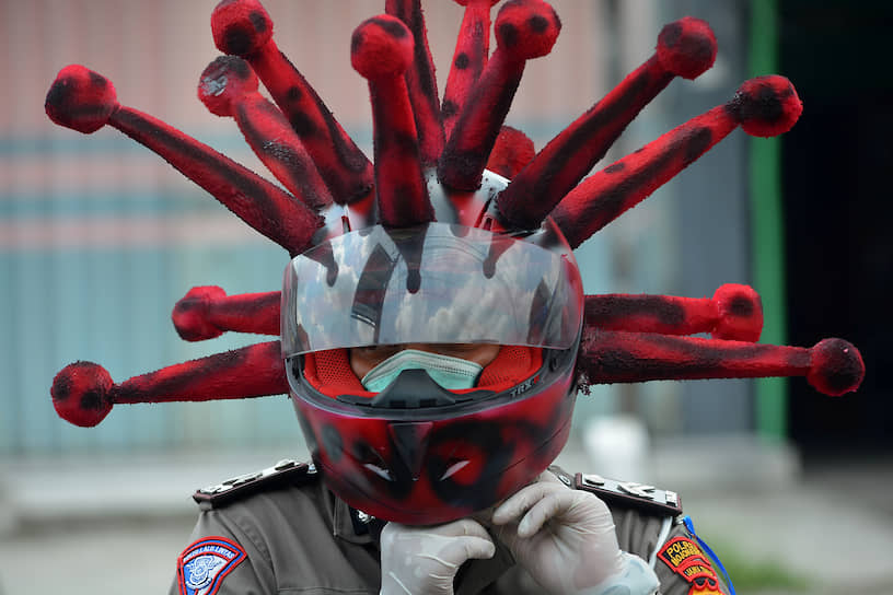 Моджокерто, Индонезия. Полицейский в шлеме, напоминающем коронавирус
