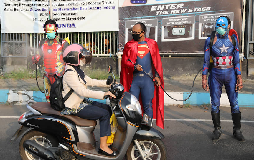 Пасуруан, Индонезия. Полицейские в костюмах супергероев дезинфицируют проезжающих