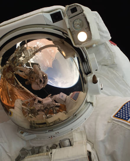 Астронавты Джон Грюнсфелд и Эндрю Фейстел (в отражении) в открытом космосе во время технического обслуживания космического телескопа Hubble