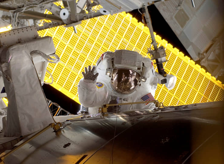 Астронавт Николь Стотт во время выхода в открытый космос на фоне солнечных панелей Международной космической станции
