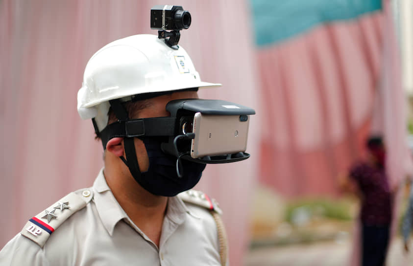 Нью-Дели, Индия. Полицейский со специальным прибором для измерения температуры тела 