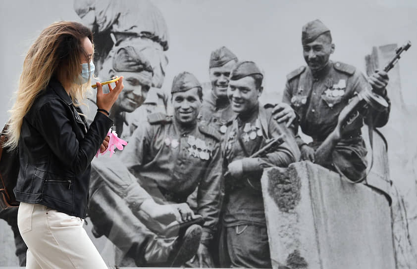 Москва. Девушка в маске на фоне плаката ко Дню Победы