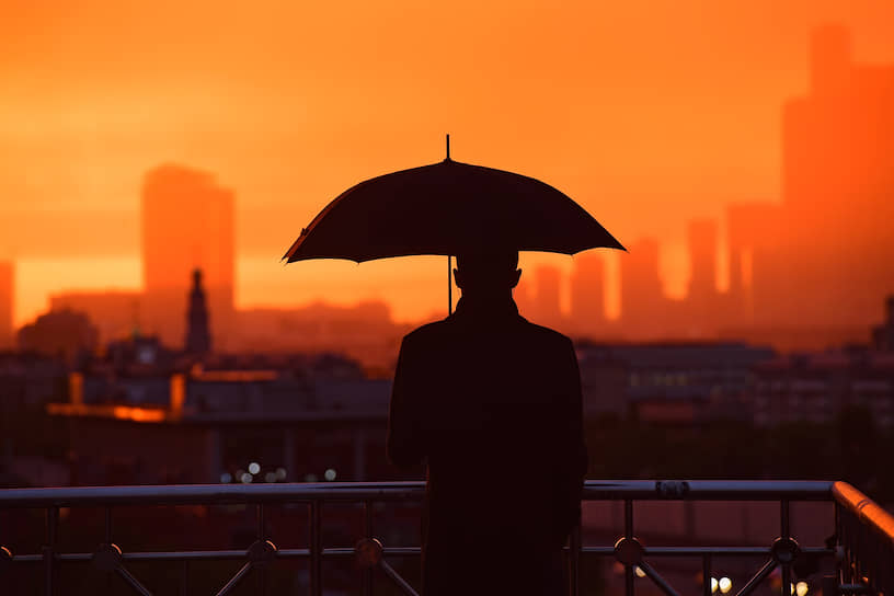 Москва. Силуэт мужчины с зонтом на фоне закатного неба