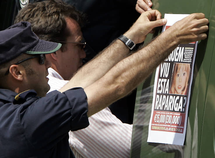 Португальский полицейский вешает плакат с информацией о пропавшей Мадлен Макканн